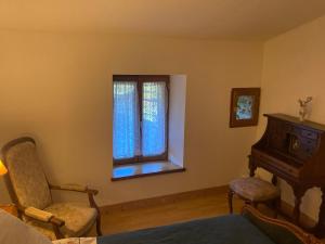 een kamer met een raam, een stoel en een piano bij Chez Bonneau in Nantiat