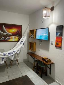 a room with a hammock and a table and a tv at Casa De Vó in Amontada +9 photos