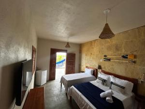 a hotel room with two beds and a television at Chalé Brisa do Pontal in Fortim