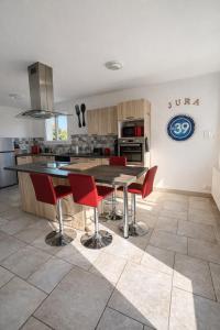 a kitchen with a wooden table and red chairs at La parenthèse in Clairvaux-les-Lacs