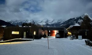 a house in the snow with mountains in the background at PurPlus Lodge in Vorderstoder