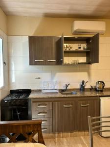 a kitchen with brown cabinets and a sink and a stove at El Atardecer in Trapiche