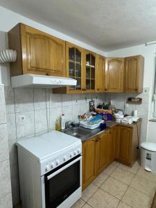 a kitchen with wooden cabinets and a white stove top oven at Apartman Jojo in Čapljina