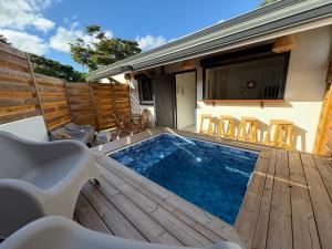 a swimming pool on a wooden deck with a table and chairs at Villa O'CAMPÊCHE in Rivière-Salée
