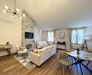a living room with white furniture and a stone wall at ROUERGAT's LITTLE GITE in Villefranche-de-Rouergue