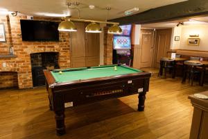 a room with a pool table and a fireplace at Monk and Tipster in Towcester
