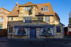 a stone building with a monkey faster sign on it at Monk and Tipster in Towcester