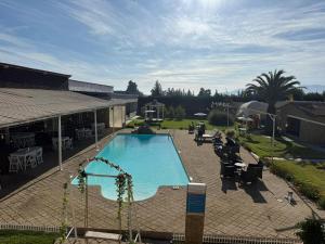 ein großer Swimmingpool in einem Garten mit einem Gebäude in der Unterkunft Hotel Origenes in Vallenar