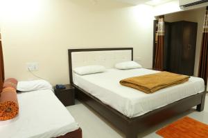 a bedroom with two beds with white sheets at SV Grand in Proddatūr
