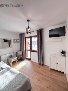 a bedroom with a bed and a tv on the wall at Willa Wincentówka w sercu Uzdrowiska in Szczawnica