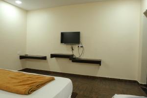 a room with a bed and a tv on the wall at SV Grand in Proddatūr