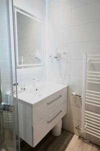 een witte badkamer met een wastafel en een spiegel bij Hotel Landhaus Dierkow in Rostock