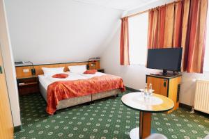 een hotelkamer met een bed en een flatscreen-tv bij Hotel Landhaus Dierkow in Rostock