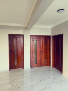 three wooden doors in a room with a tile floor at Nordik Hotel in Nkumba +8 photos
