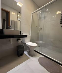 een badkamer met toilet en glazen douche bij RM hospedagem unidade Amapá 2 in Cabo Frio