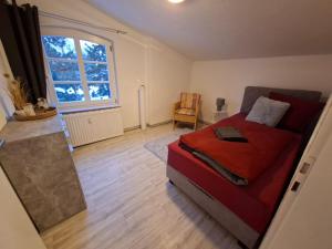a bedroom with a red bed and a large window at FeWo im Herzen Tarnows in Tarnow