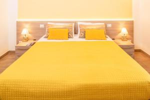 een groot geel bed in een slaapkamer met twee lampen bij MillyHolidays - Apartment Sunflower - Center - Nearby Beach - Private Garden - Spa Pool in Bardolino