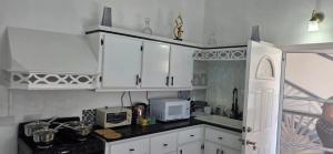 a kitchen with white cabinets and a microwave at Martha's House Lexus in Soufrière