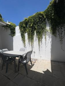 a table and chairs on a patio with ivy on a wall at Hermoso PH en Necochea playa in Necochea