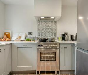 a kitchen with white cabinets and a stainless steel oven at Fig Tree Cottage - Corfe Castle in Corfe Castle