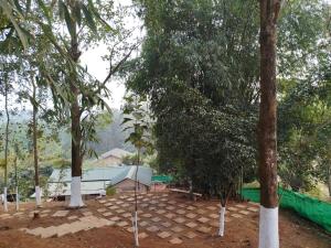 a park with trees and a building in the background at Mur Farm House in Sonāpur