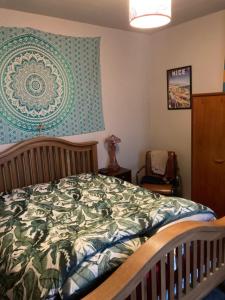 a bedroom with a bed with a green and white comforter at Step-free modern central apartment in Todmorden