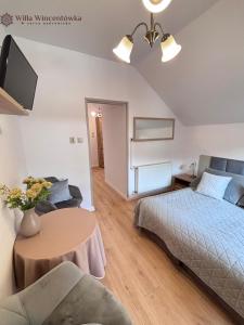 a bedroom with a bed and a table and a tv at Willa Wincentówka w sercu Uzdrowiska in Szczawnica