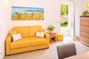 a living room with a yellow couch and a table at MillyHolidays - Apartment Sunflower - Center - Nearby Beach - Private Garden - Spa Pool in Bardolino
