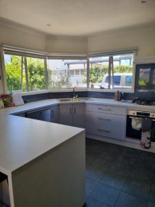 a kitchen with a white counter and some windows at Norfolk House in Gisborne