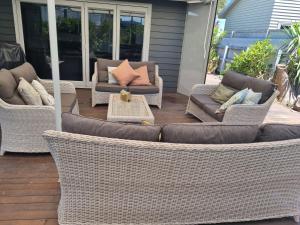 a patio with wicker chairs and couches on a porch at Norfolk House in Gisborne