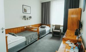 a hotel room with two beds and a chair at Hotel Polonia Racibórz in Racibórz