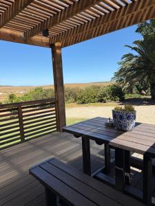 a wooden deck with a picnic table and a pergola at De Gunst Guest Farm in Malmesbury