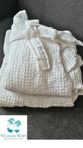 una coperta bianca lavorata a maglia è appoggiata sul pavimento di Világos Kert Garden Suites -Balatonvilágos a Balatonvilágos