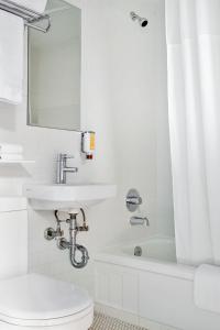 a bathroom with a sink and a toilet and a mirror at The Burrard in Vancouver