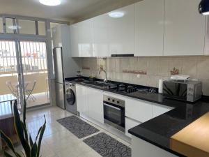 a kitchen with white cabinets and a stove top oven at Hendy's cozy apt in Praia