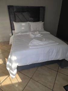 a large white bed with white sheets and pillows at The Good Samaritan 4 in eMalahleni