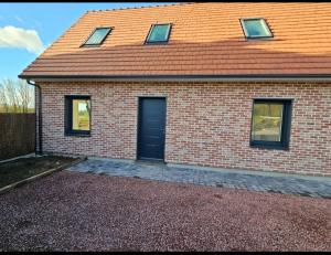 a brick house with a black door and a roof at Gîte Familial in Nabringhen