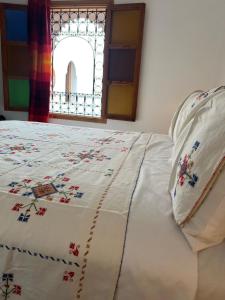 a bed with a quilt on it with a window at Riad Tafoukt Palace in Fez
