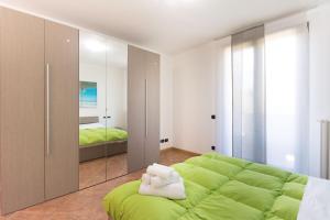 a bedroom with a large green bed and a mirror at villa between lake and mountains in Valbrona