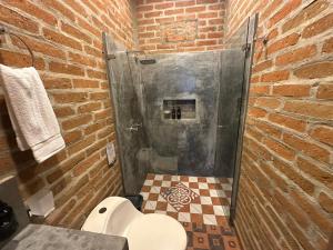 un bagno con doccia e WC in un muro di mattoni di Eco Hotel La Colina Mirador Con aire acondicionado a Quimbaya