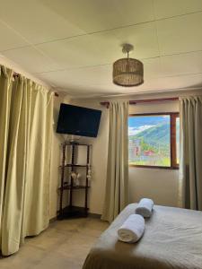 a bedroom with a bed and a flat screen tv at Cabañas Tafi in Tafí del Valle