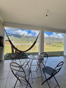a patio with a table and chairs and a hammock at Cabañas Tafi in Tafí del Valle