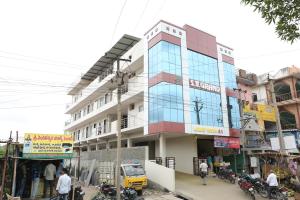 a building on a city street with people and motorcycles at SV Grand in Proddatūr