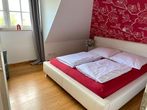 a bed in a room with a red wall at Reetdachhaus Windblume - super gemütlich in Zinnowitz