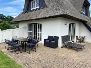 a patio with a table and chairs in front of a house at Reetdachhaus Windblume - super gemütlich in Zinnowitz