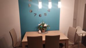 a dining room table with chairs and a clock on the wall at Apartmán Všemina 14A in Všemina
