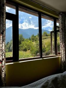 a bedroom window with a view of a mountain at Dreamland Cottage in Pahalgām +18 photos