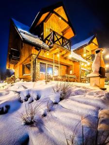 a log cabin in the snow at night at Bieszczadzka Hawira - w Centrum przy Jeziorze z Widokiem dla Rodzin in Polańczyk