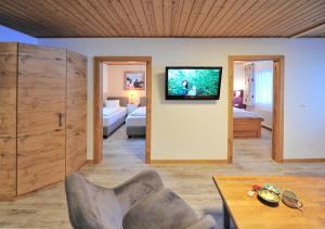 un soggiorno con un divano e una TV a parete di Appartements & Chalets Wiesenruh a Bichlbach