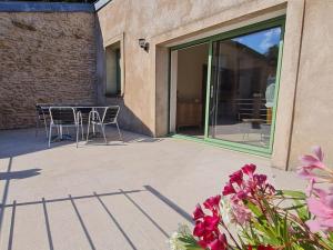 a patio with a table and chairs and a window at L' Échappée Miel in Laitre-sous-Amance